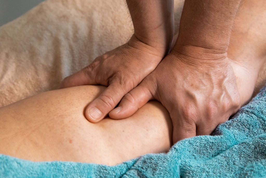 Man giving a massage to a leg with two hands.